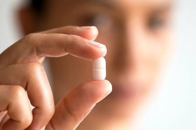 Mão segurando um comprimido, representando a terapia hormonal
